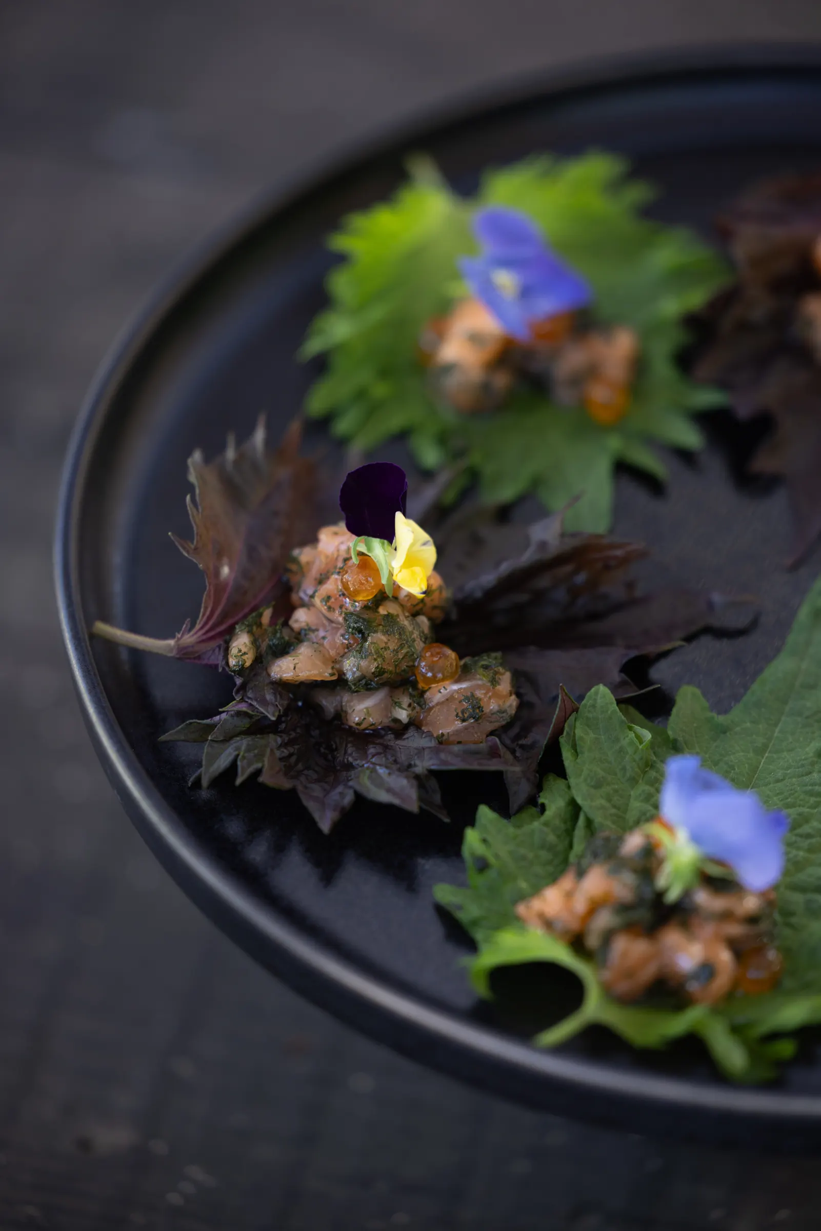 Dark plate of canapés topped with flowers