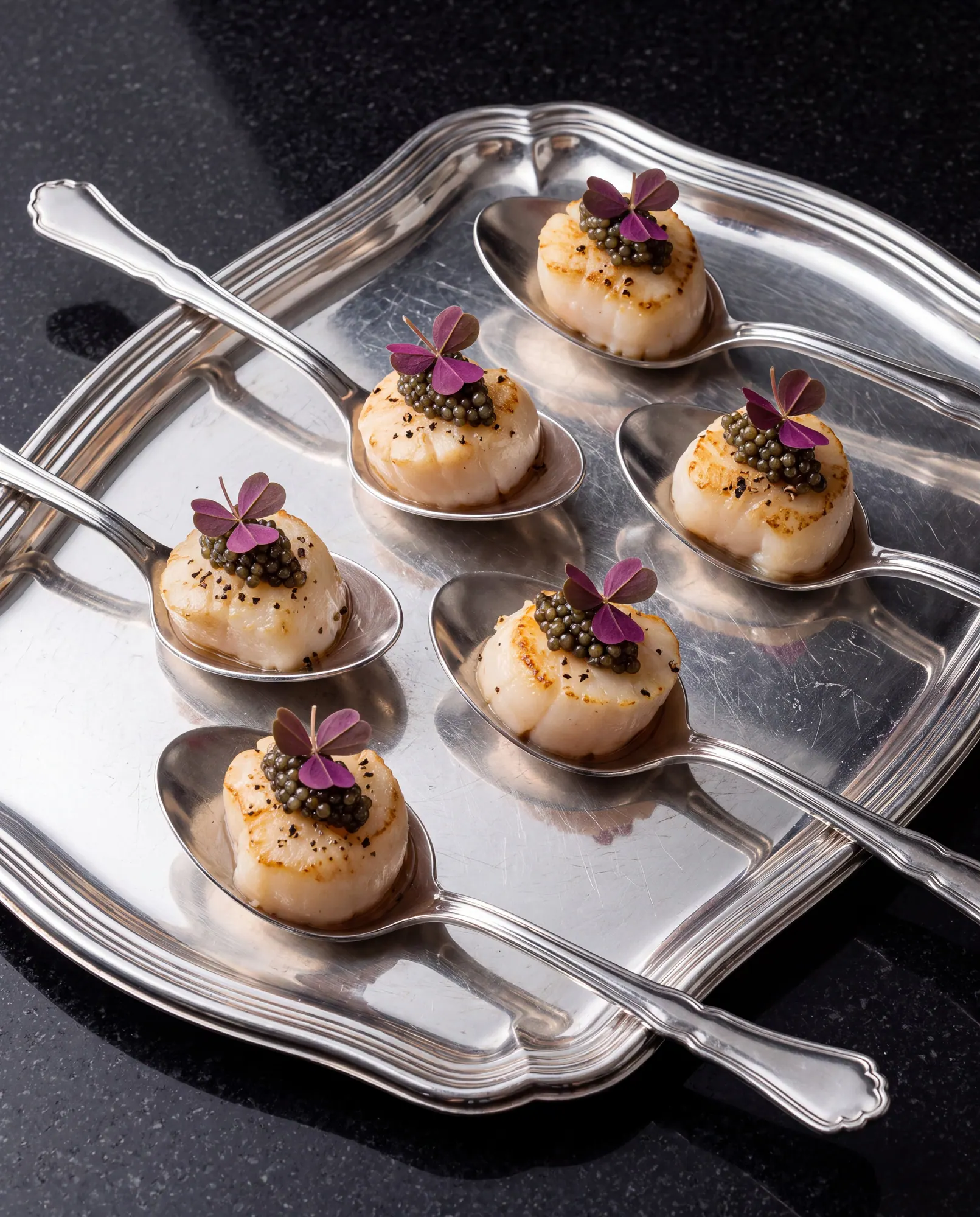Scallop canapés on spoons, caviar and oxalis