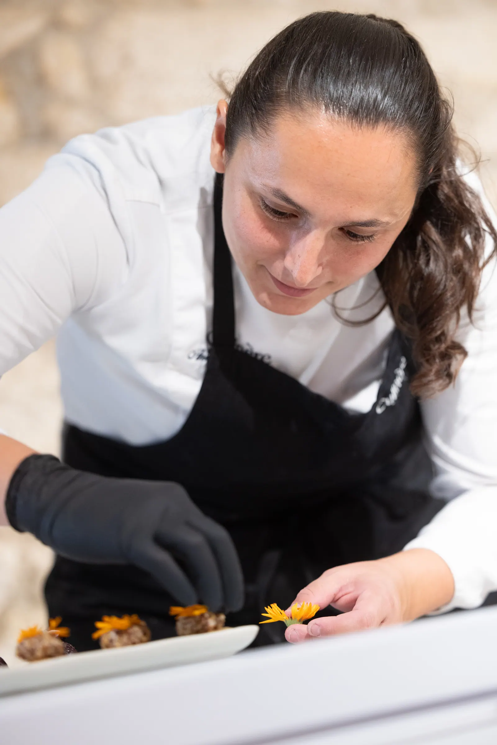 Anissa Boulesteix plating, smiling and focused, edible flowers